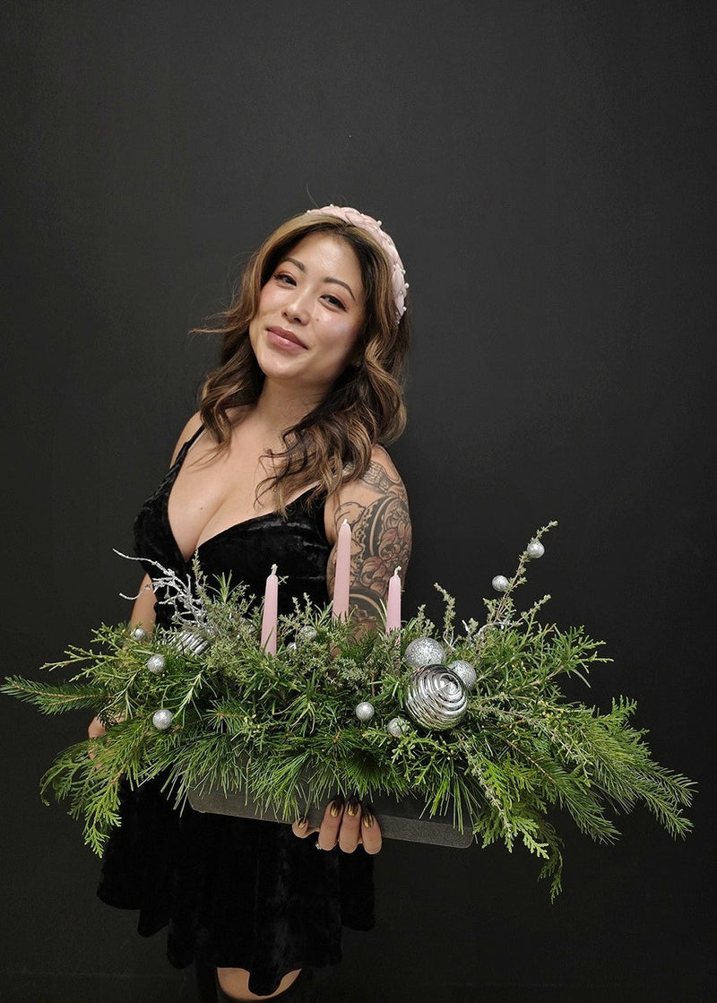 holiday festive floral arrangement with candles against a black background