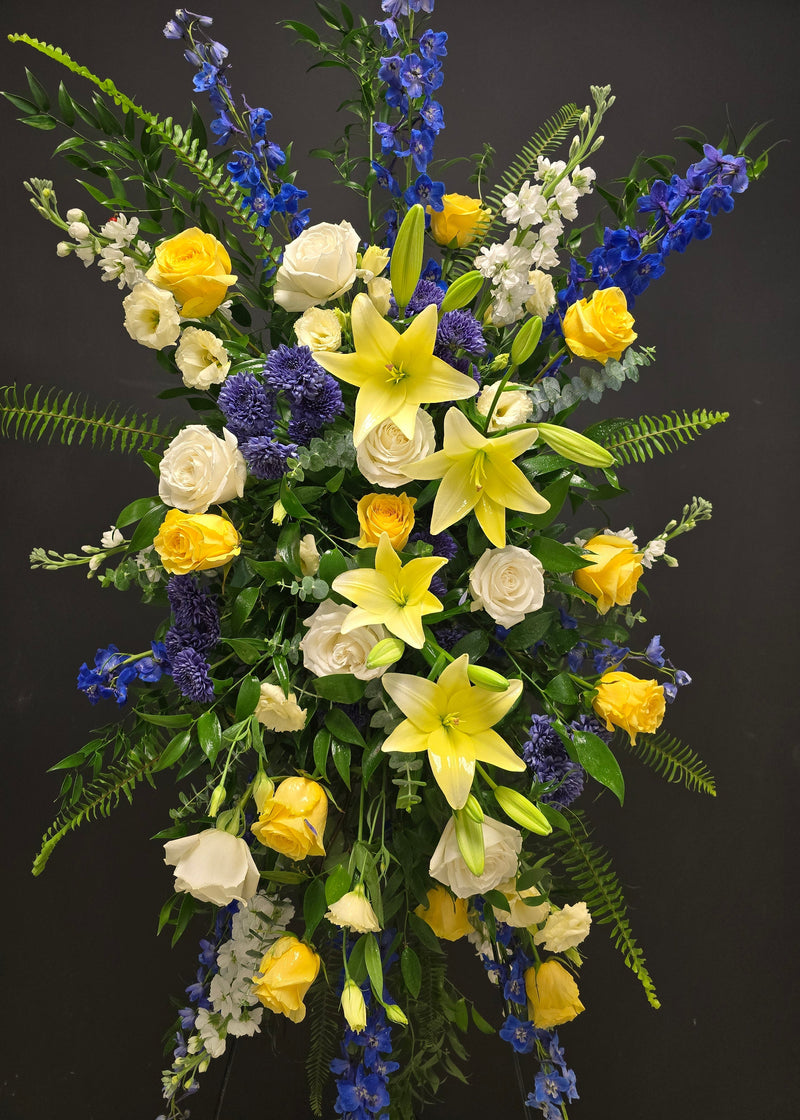 sympathy funeral celebration of life arrangement of yellow, white, blue flowers standing spray 